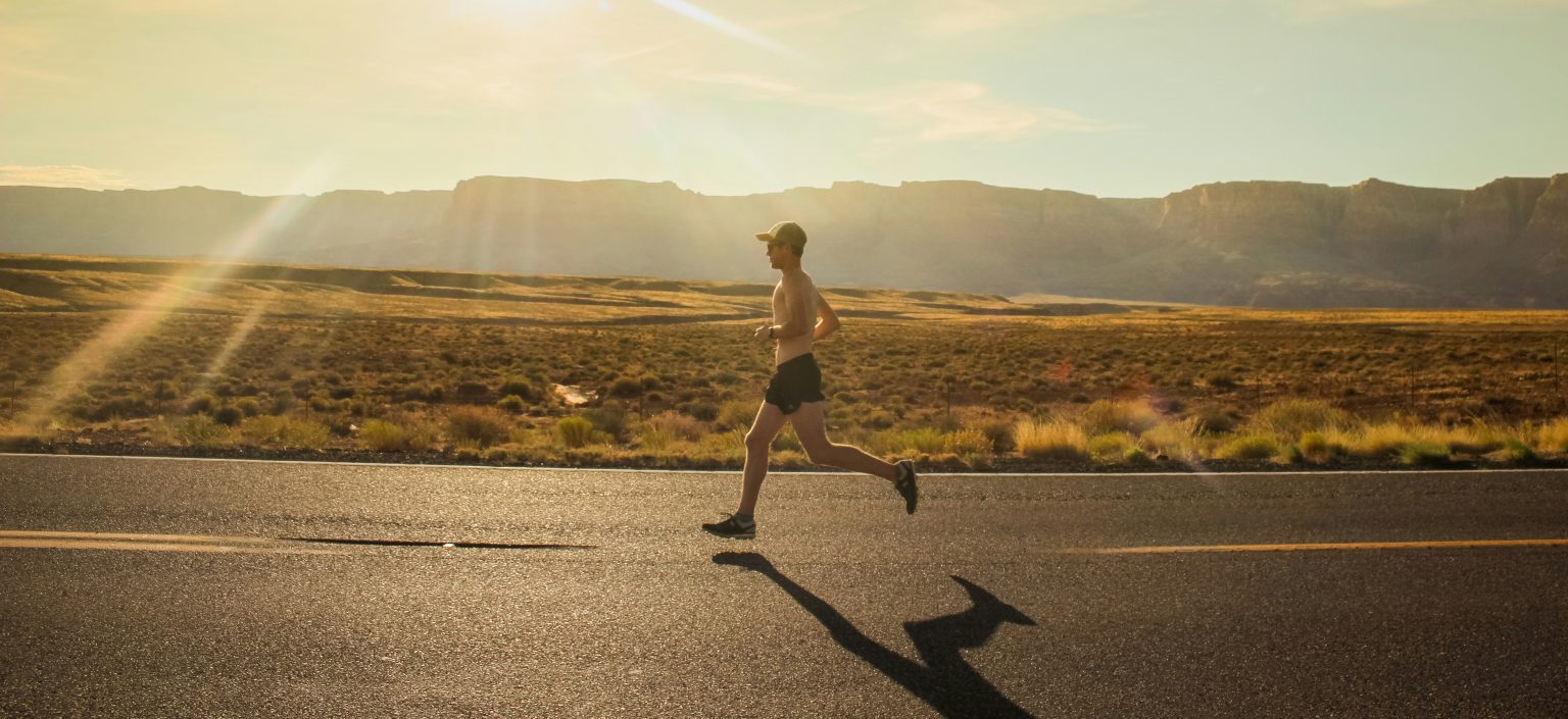 Un uomo che corre lungo una strada durante il tramonto