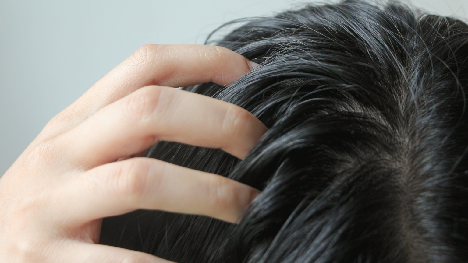 Il dettaglio di una tesyta e una mano tra i capelli grassi