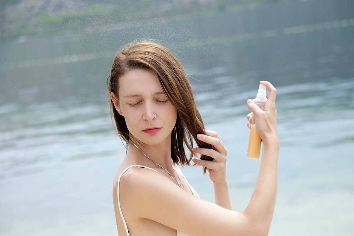 Una ragazza che spruzza un protettivo sui capelli