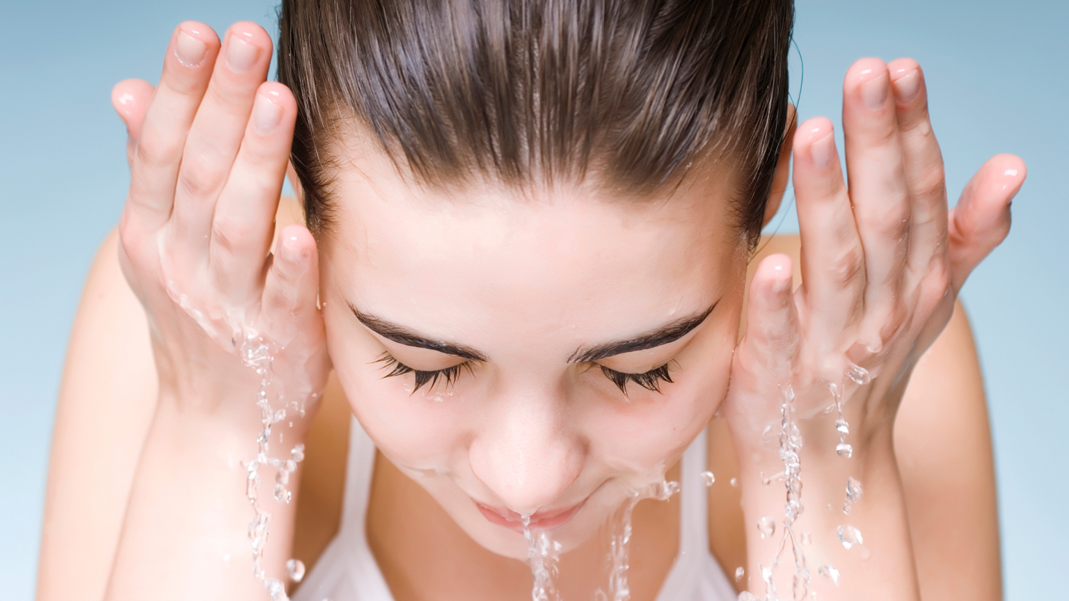 Una ragazza che si bagna il viso con acqua