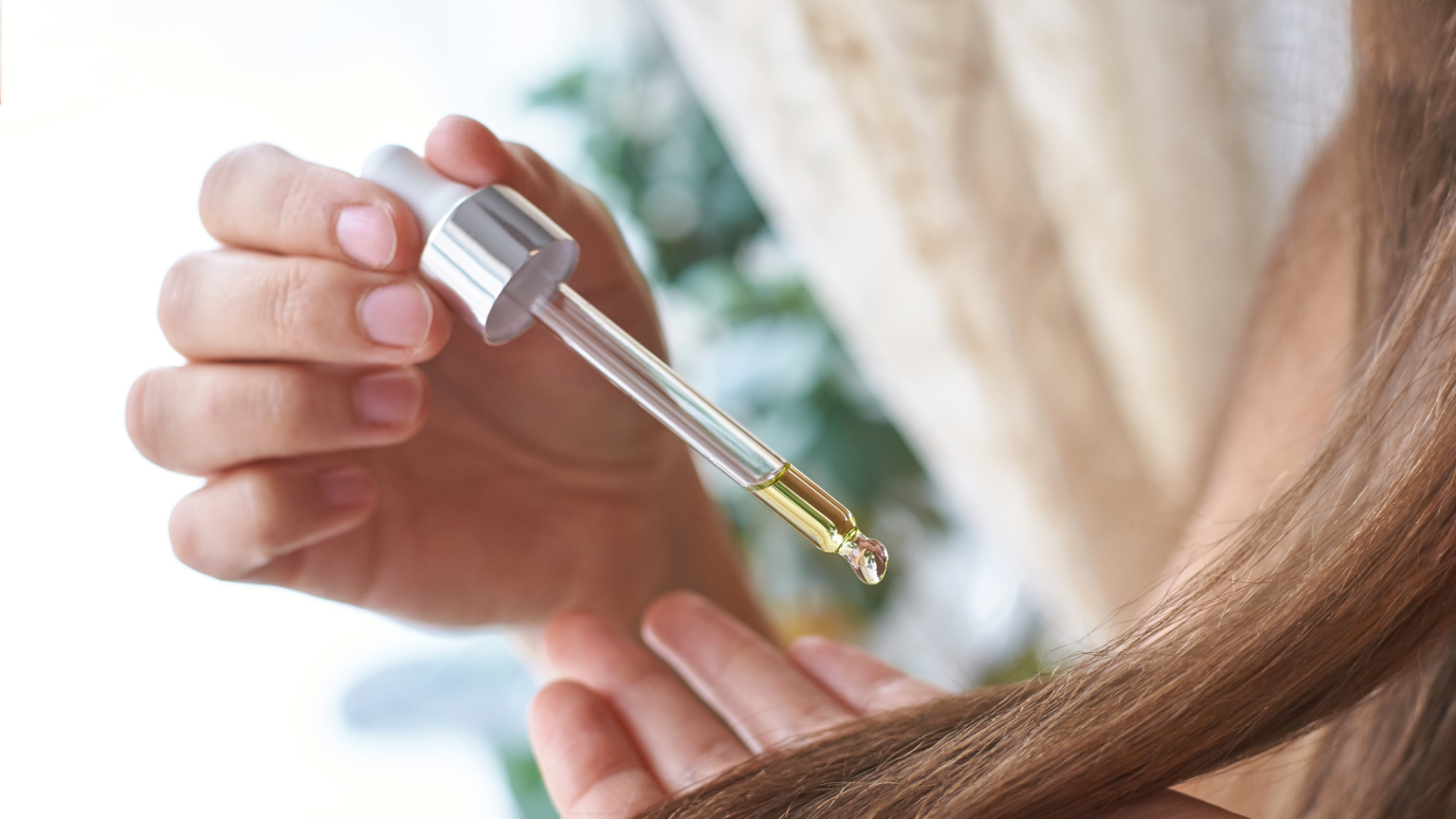 Il dettaglio di una ciocca di capelli su cui si sta mettendo del siero con un contagocce