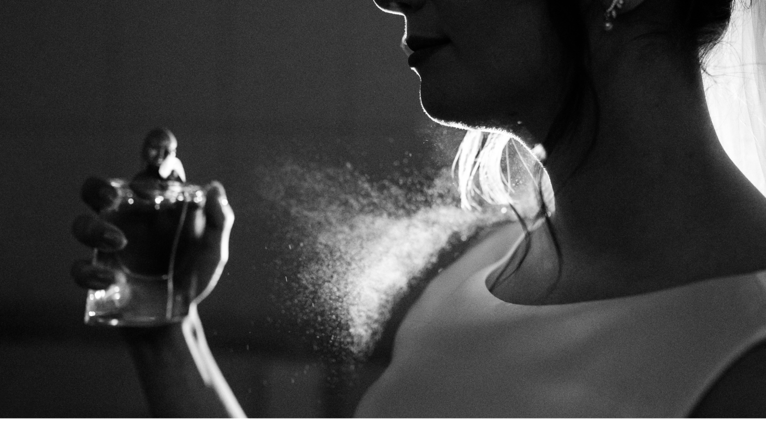 La sagoma di una donna che si spruzza del profumo in una foto in bianco e nero